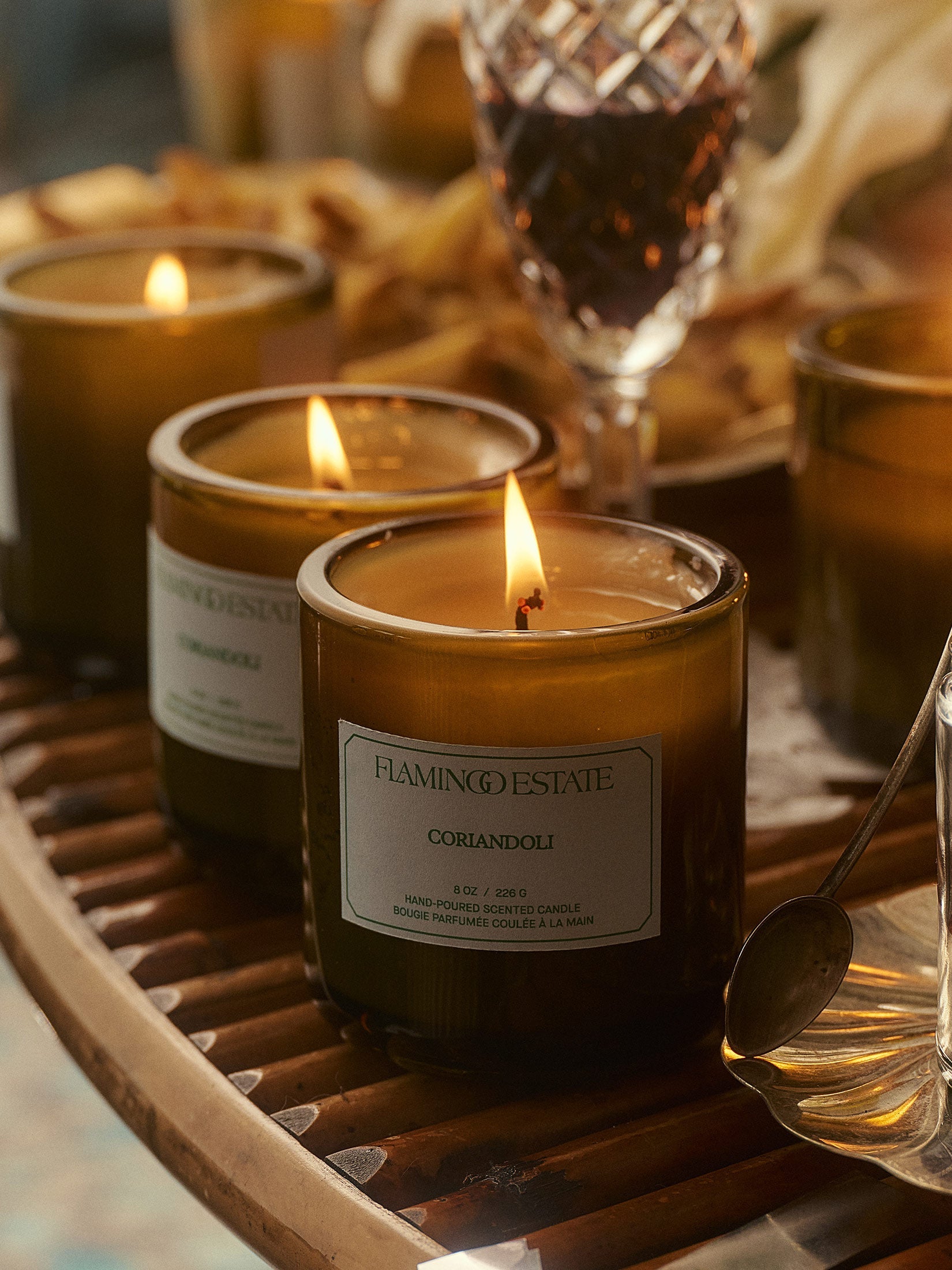 Three lit candles on a table with glasses and food.