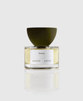 A bottle of Rotano Eau de Parfum by Maison d'Etto with a clear liquid visible inside, a white label, and a green cap.