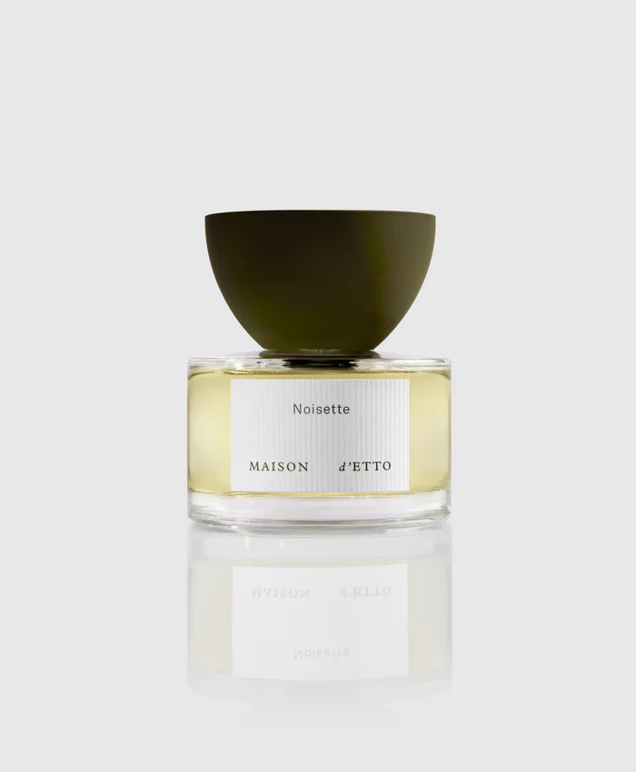 A bottle of Noisette Eau de Parfum by Maison d'Etto with a clear glass and a green cap, displaying the label and the perfume inside.