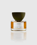 A bottle of 'Verdades Eau de Parfum' by Maison d'Etto with a clear glass and a green cap, displaying the yellow-colored perfume.