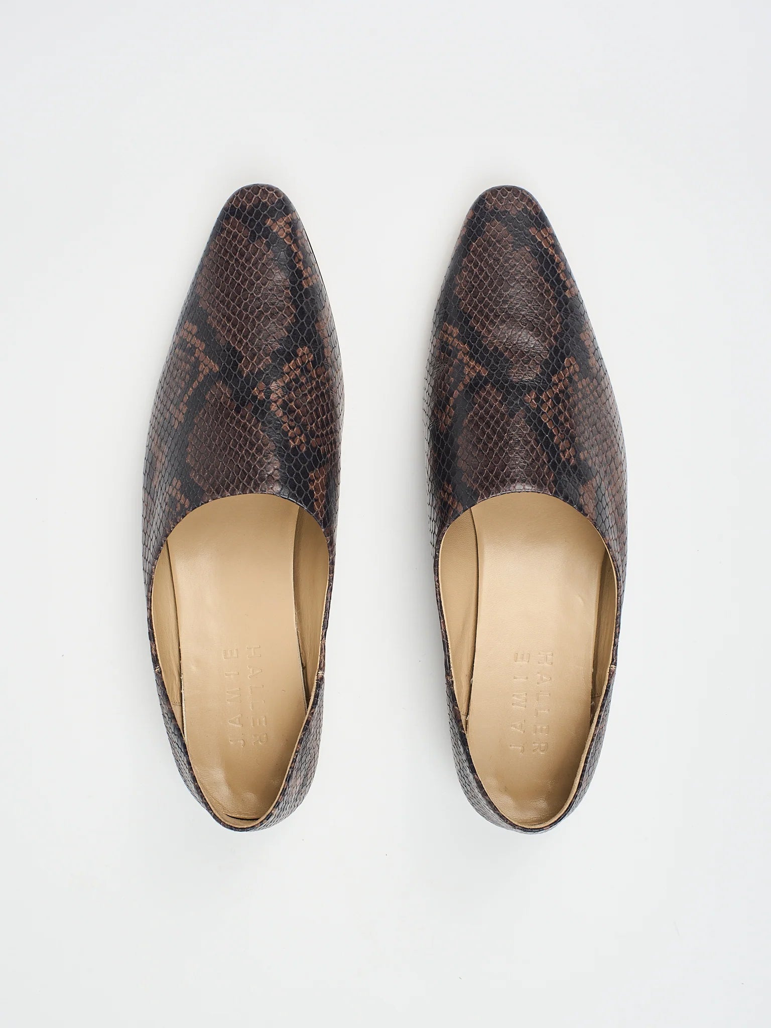 A pair of burgundy cobra patterned mules by Jamie Haller, viewed from the top, showing the pointed toe and flat sole.