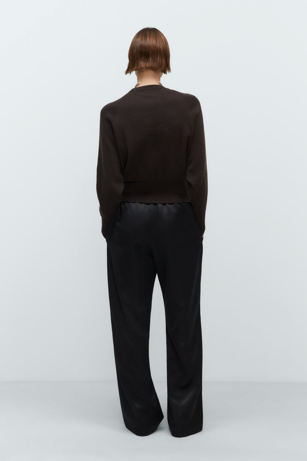 Person wearing a black cashmere sweater outfit on a white background