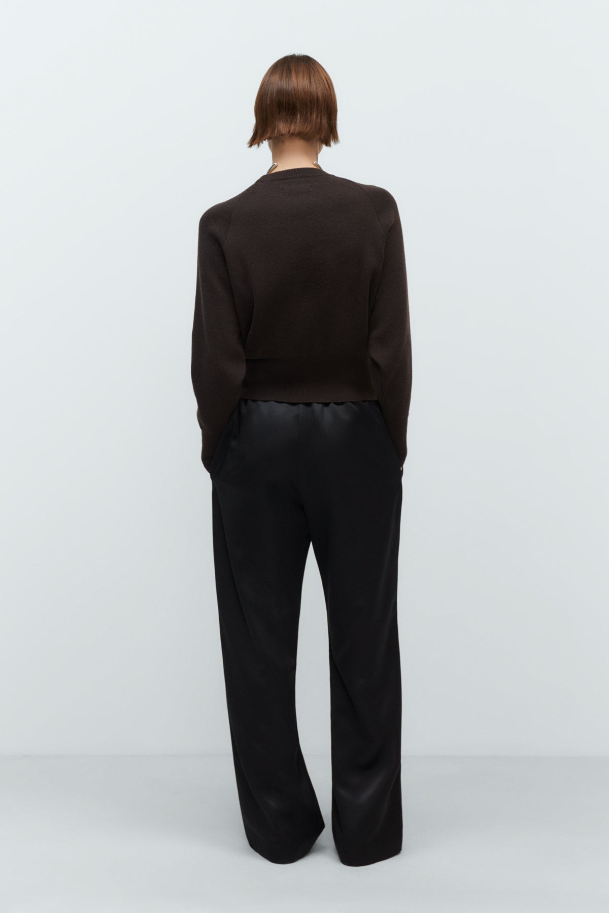 Person wearing a black cashmere sweater outfit on a white background
