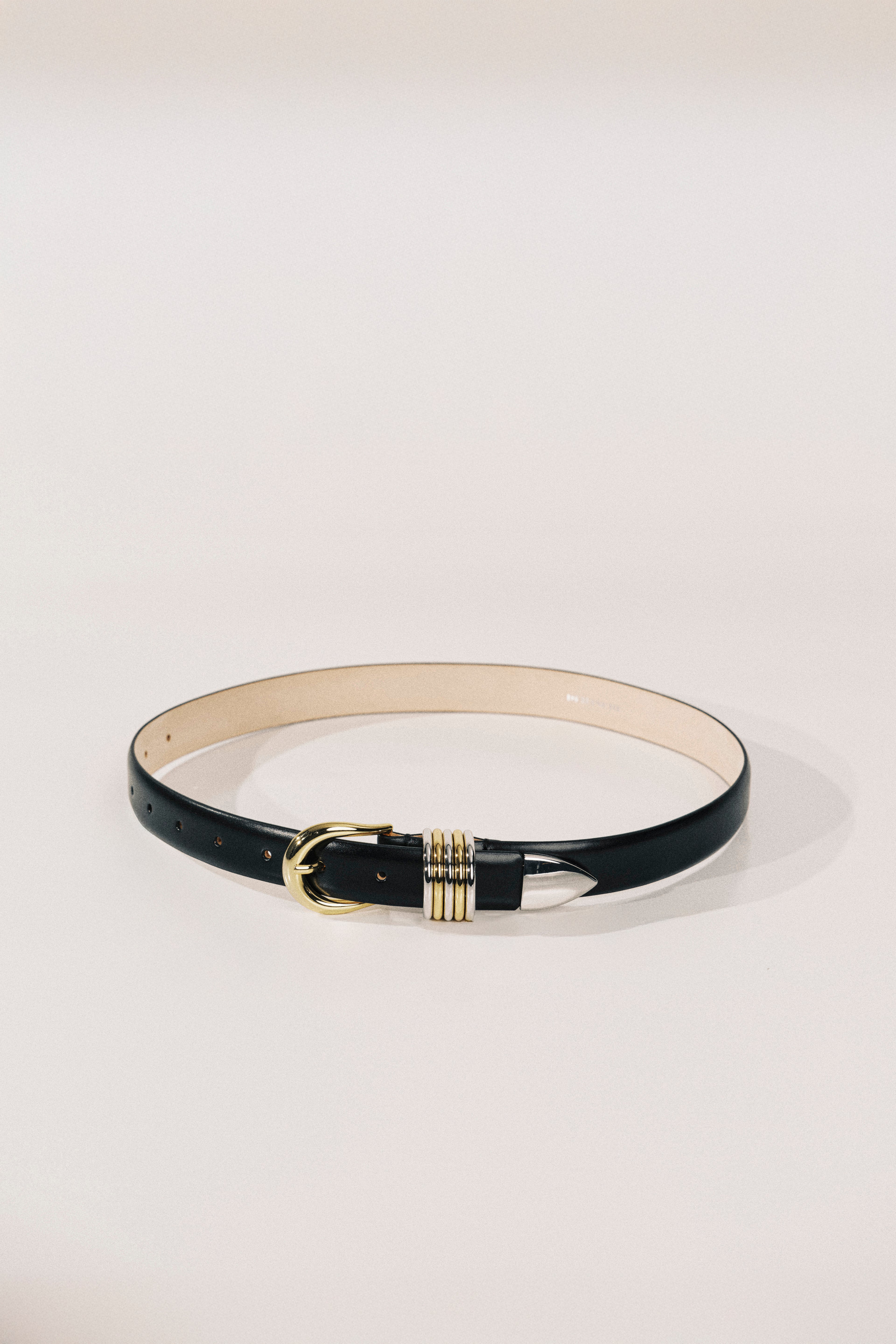 Black belt with a gold buckle on a light gray background