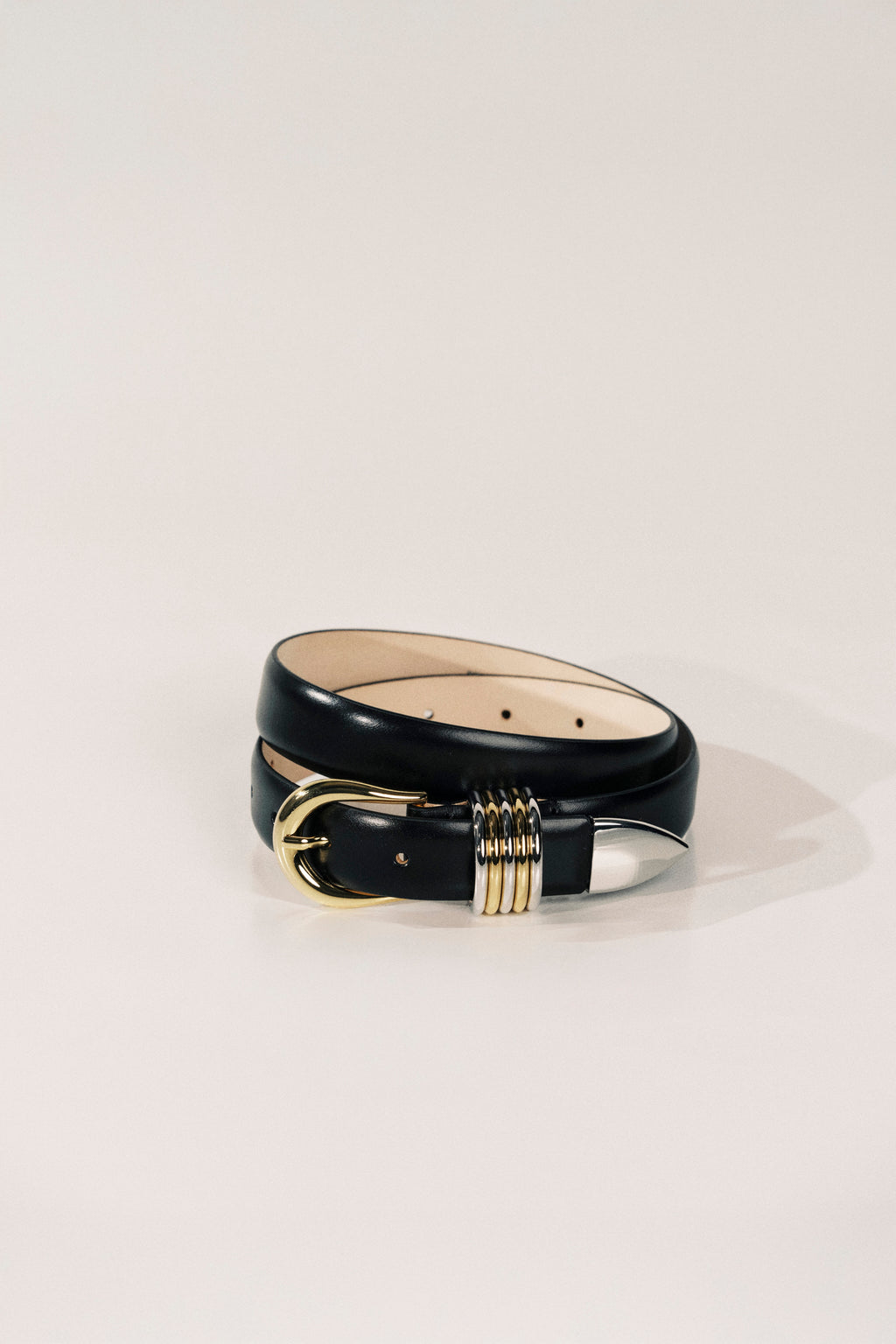 Black leather belt with gold buckle on a light beige background