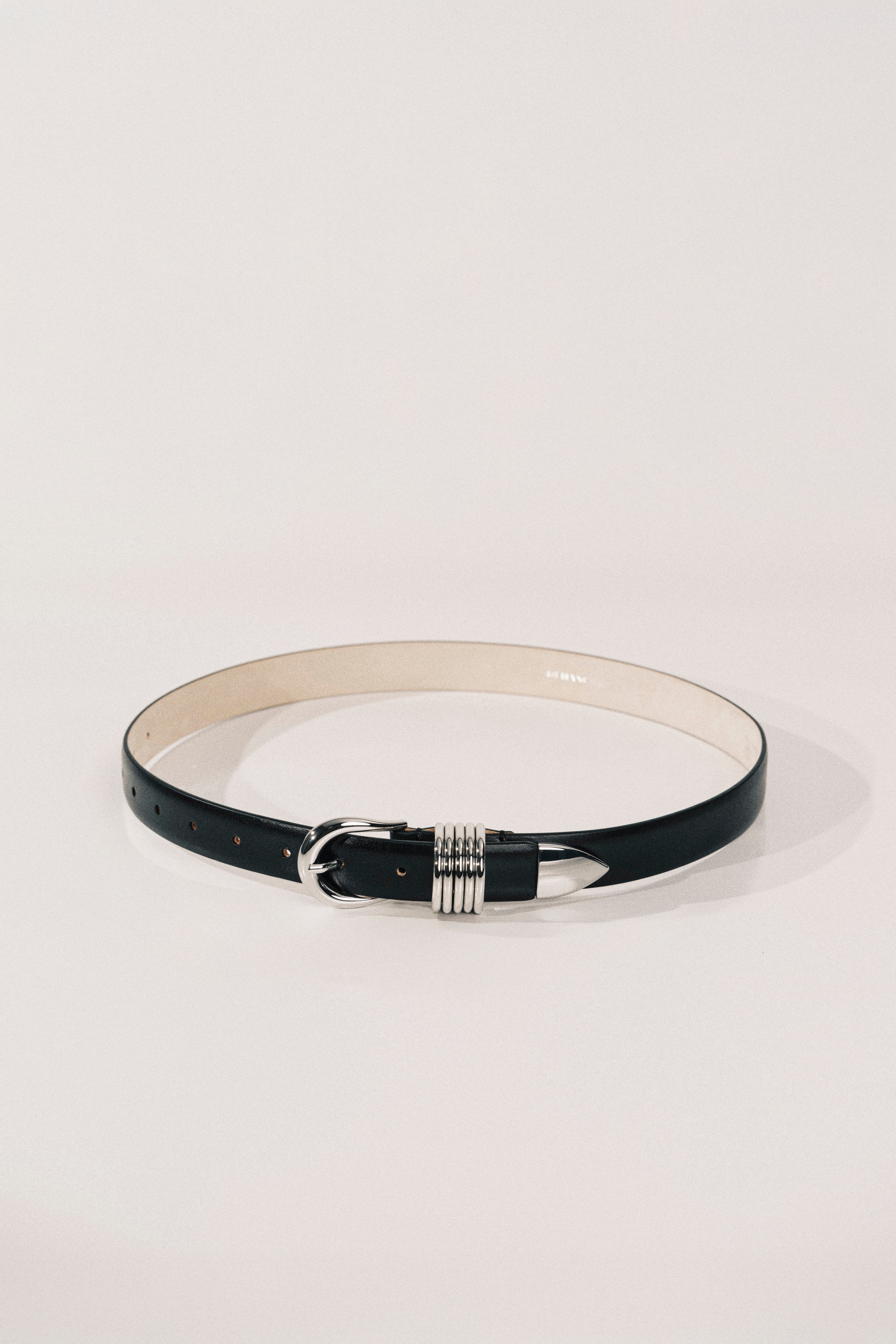 Black belt with a silver buckle on a light gray background
