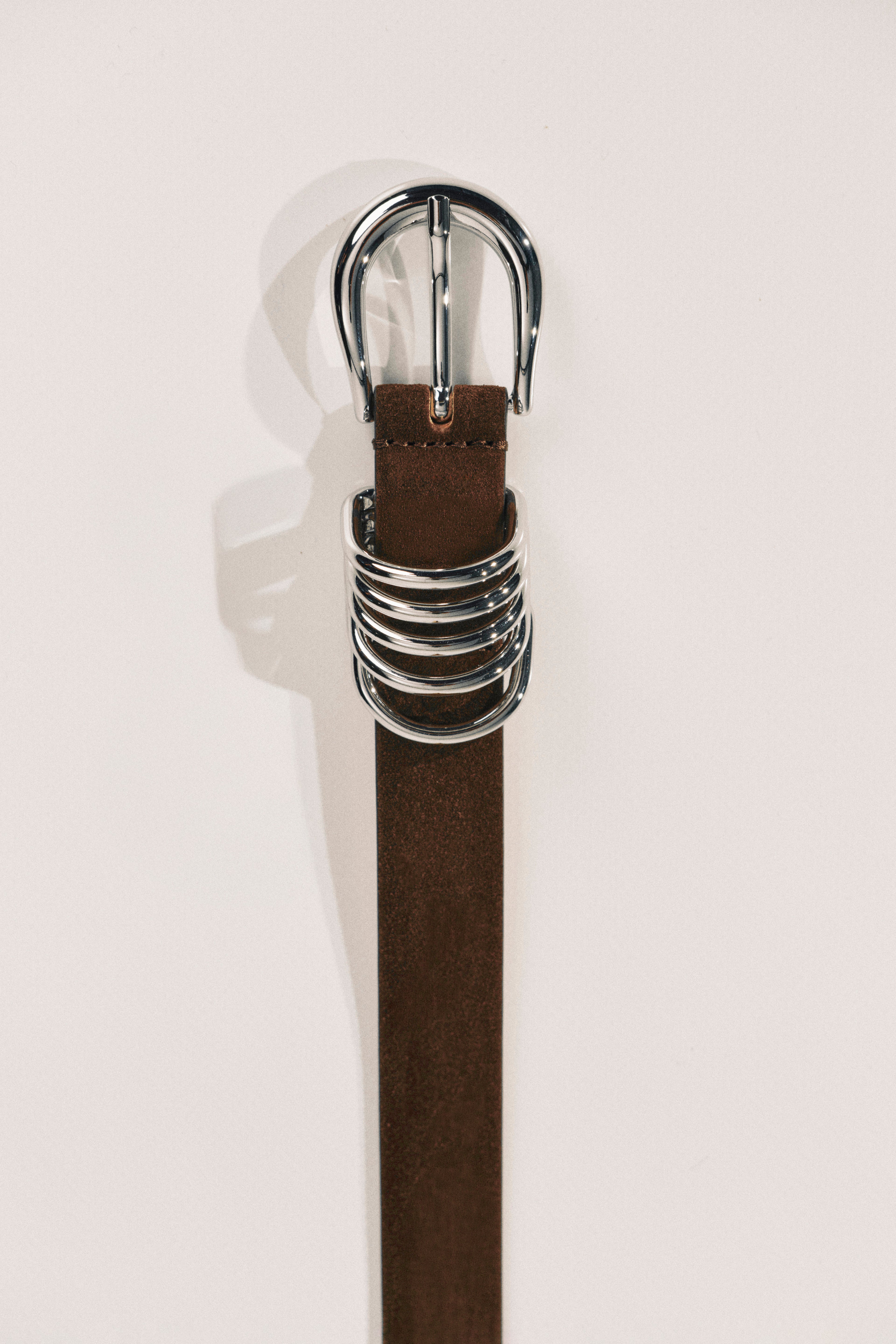 Brown belt with a silver buckle on a white background