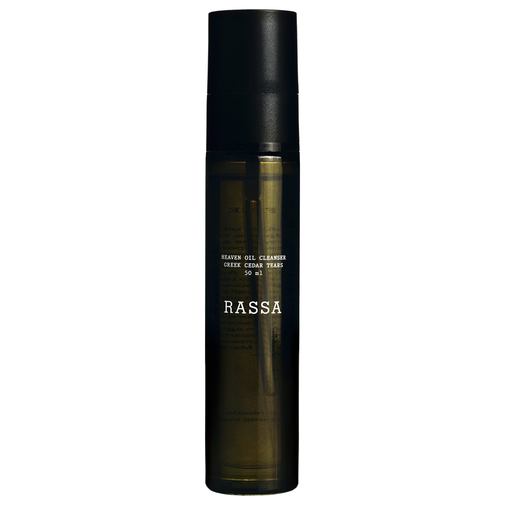 A bottle of Rassa Botanicals Heaven Oil to Milk Cleanser with a dark cap and a clear, amber-colored liquid visible through the bottle.