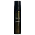 A bottle of Rassa Botanicals Heaven Oil to Milk Cleanser with a dark cap and a clear, amber-colored liquid visible through the bottle.
