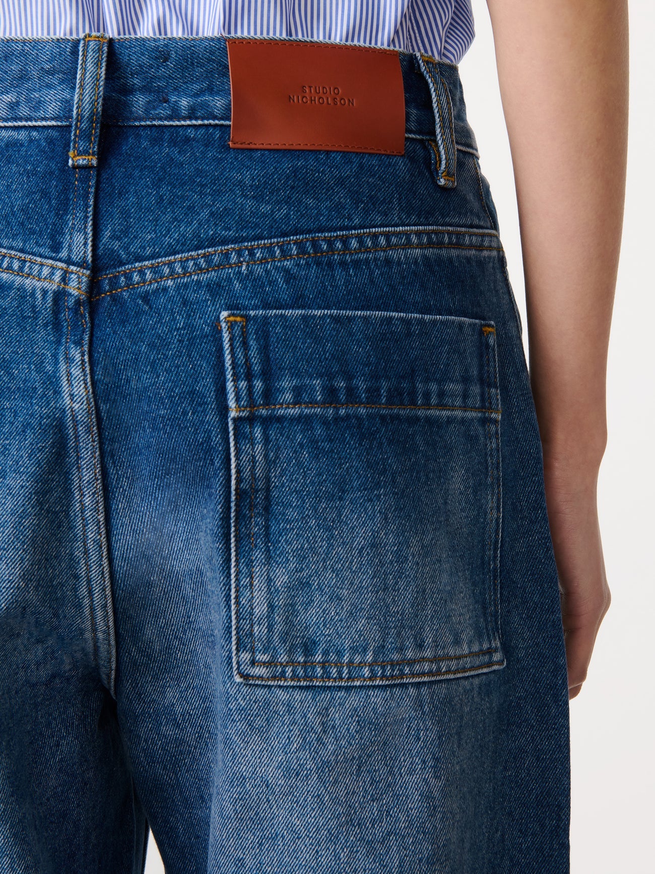 Close-up of blue jeans with a brown leather patch on a white background