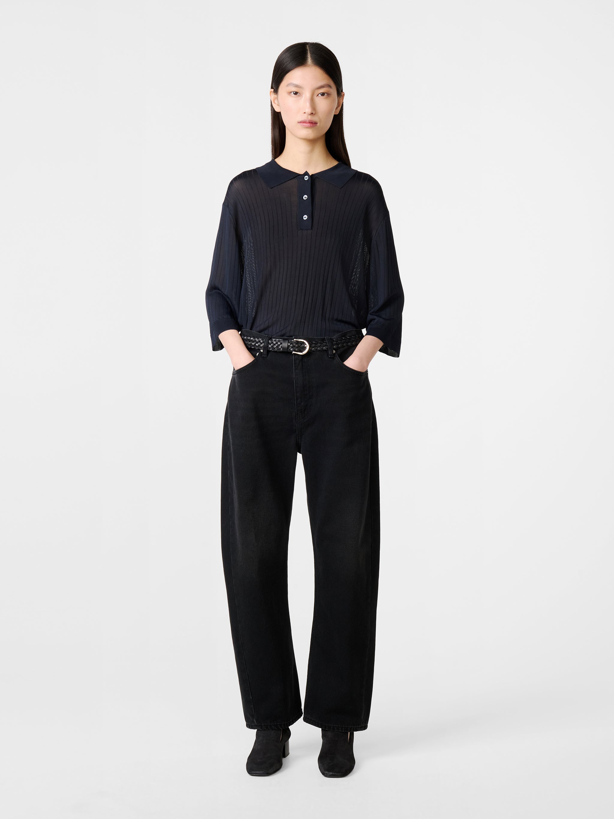 Model wearing Studio Nicholson Denjo Denim Pant in Washed Black on white background.