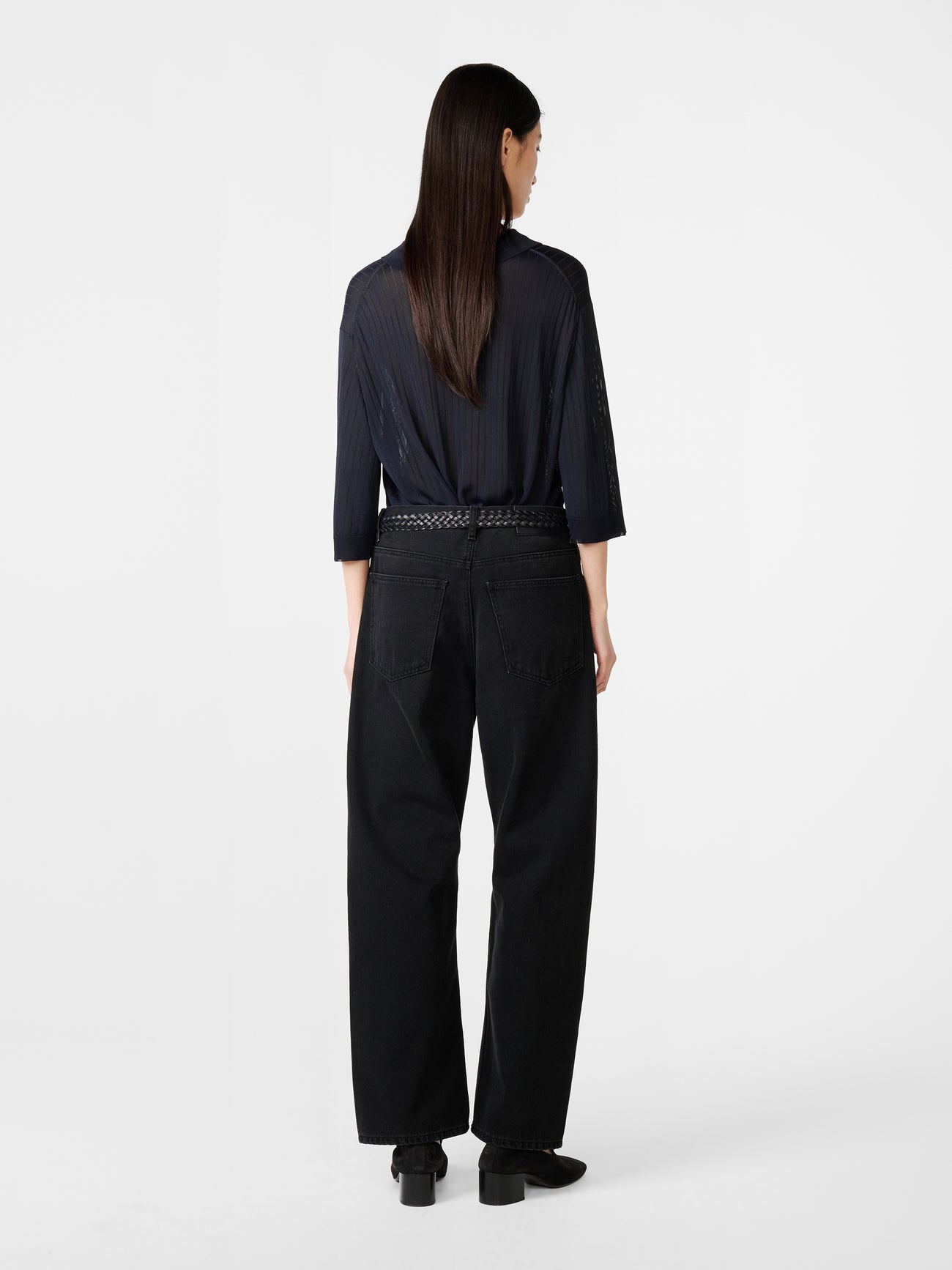 Model wearing Studio Nicholson Denjo Denim Pant in Washed Black on white background.