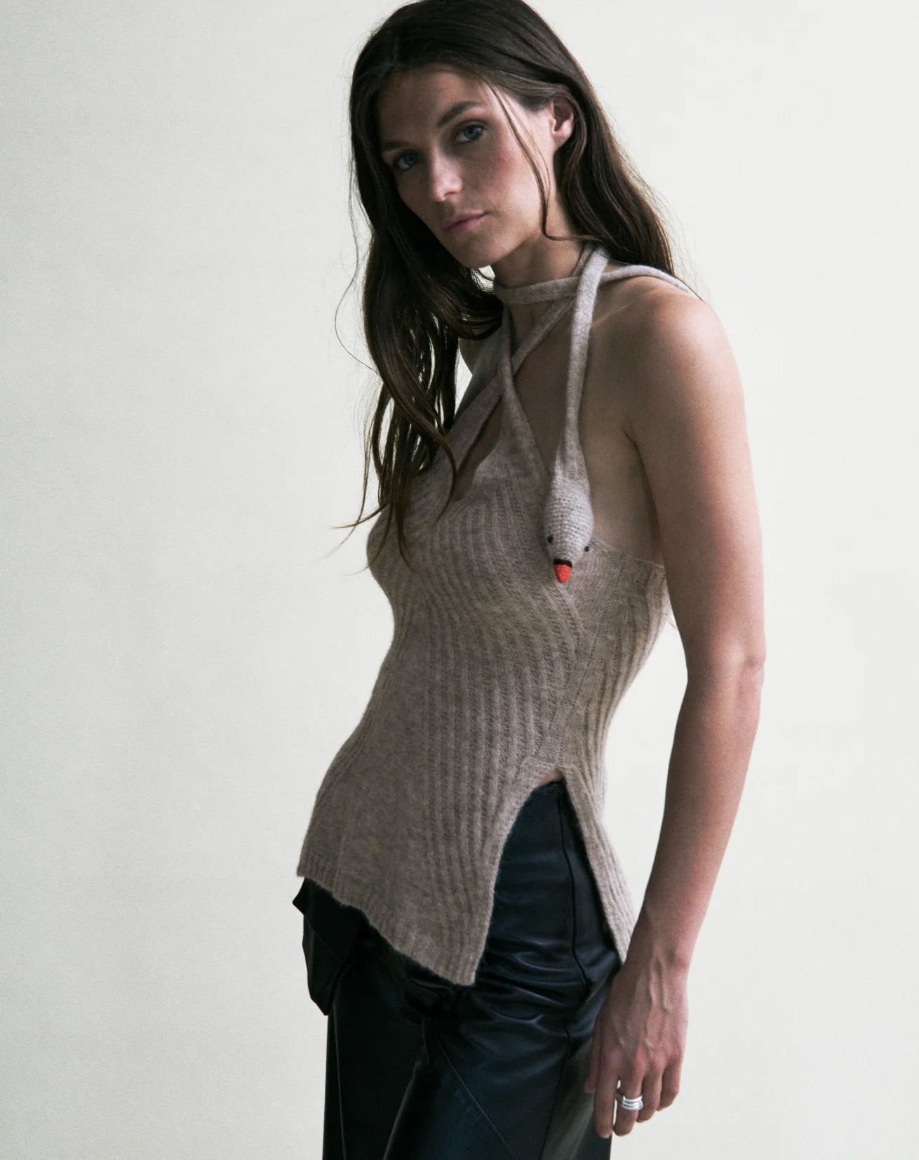 Woman wearing a sleeveless knitted top with a plain background