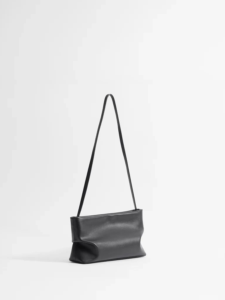 Black leather handbag with a strap on a white background