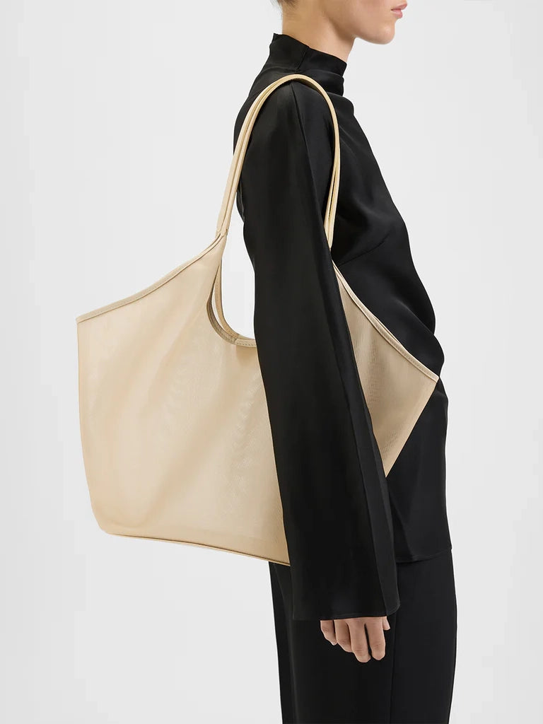 Beige tote bag worn by a person on a white background