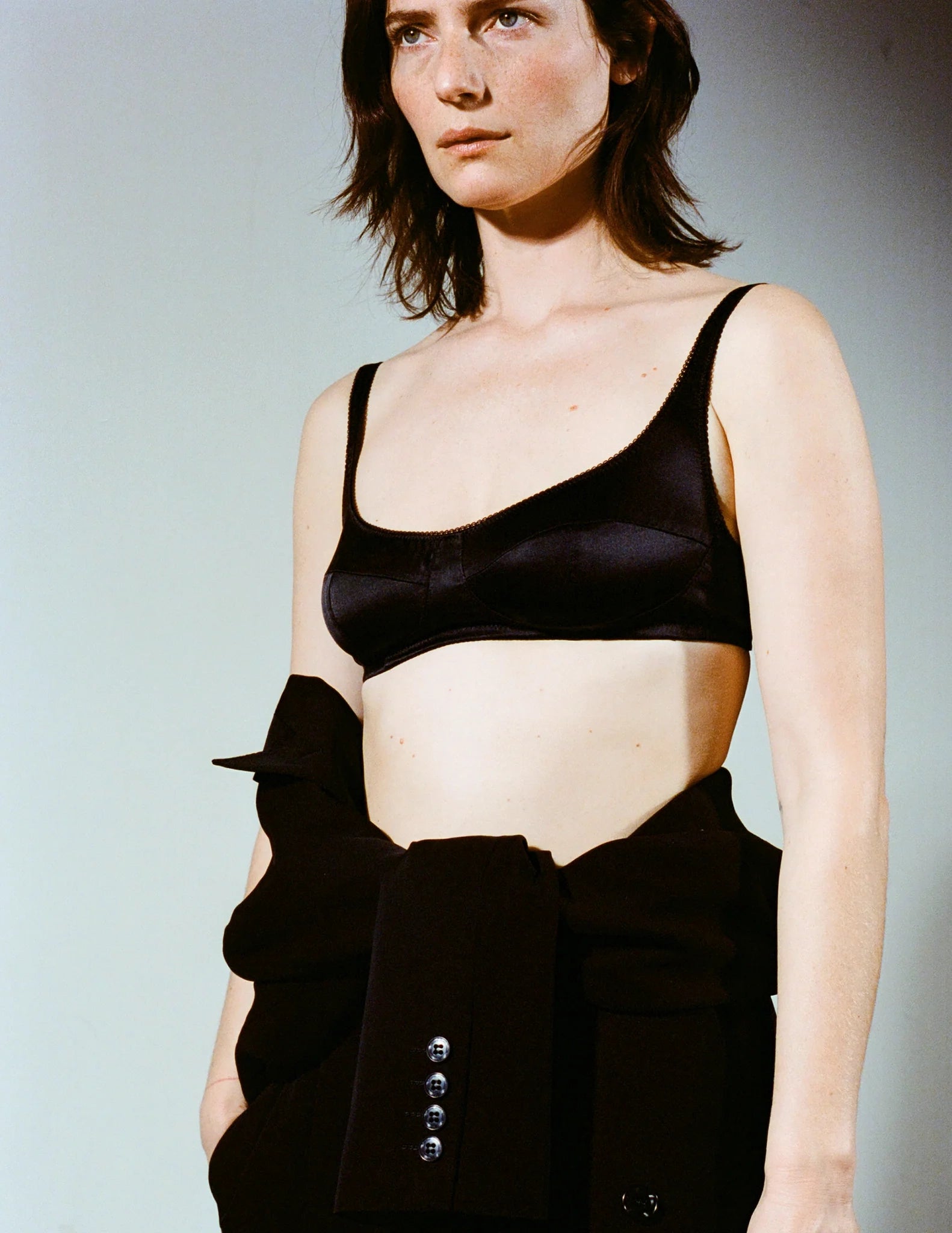 Woman wearing a black bra and high-waisted black pants against a plain background