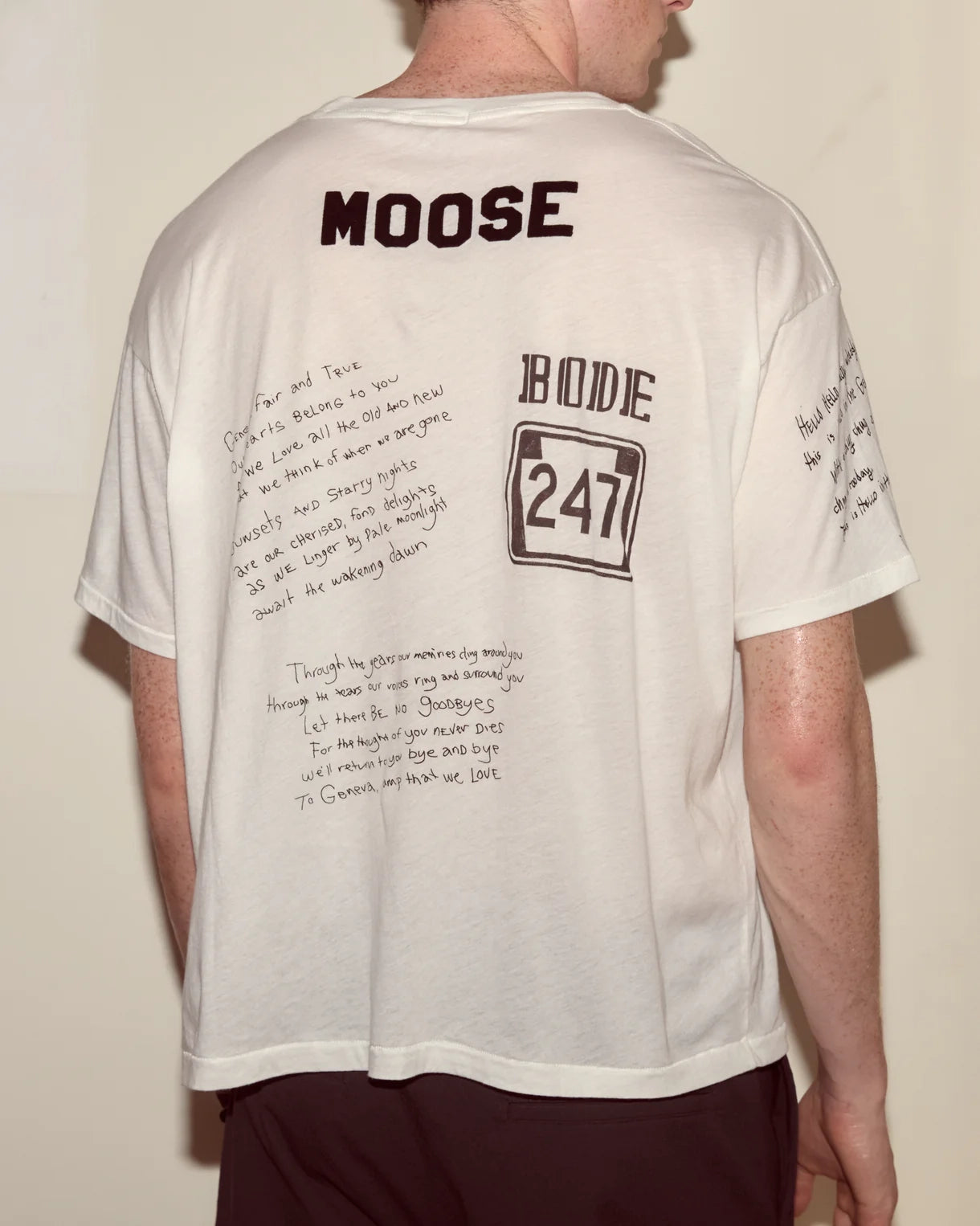Person wearing a white t-shirt with text and branding on the back.