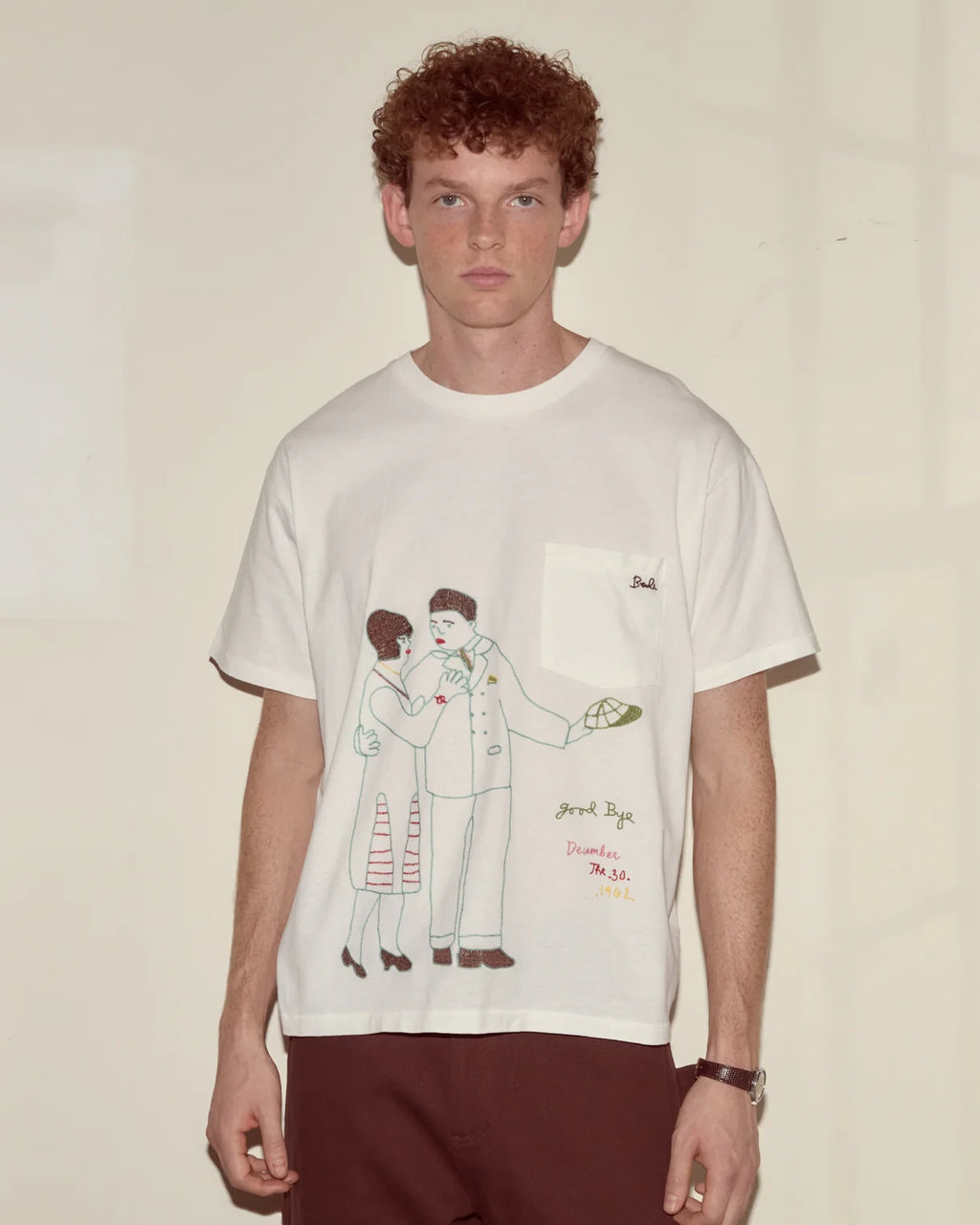 Person wearing a white t-shirt with a graphic design on a plain background