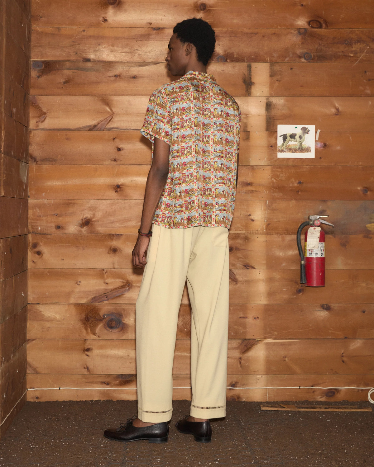 Model wearing Bode Cowboy Comic Short Sleeve Shirt in multicolor silk with a repeating cowboy comic print and front patch pocket.