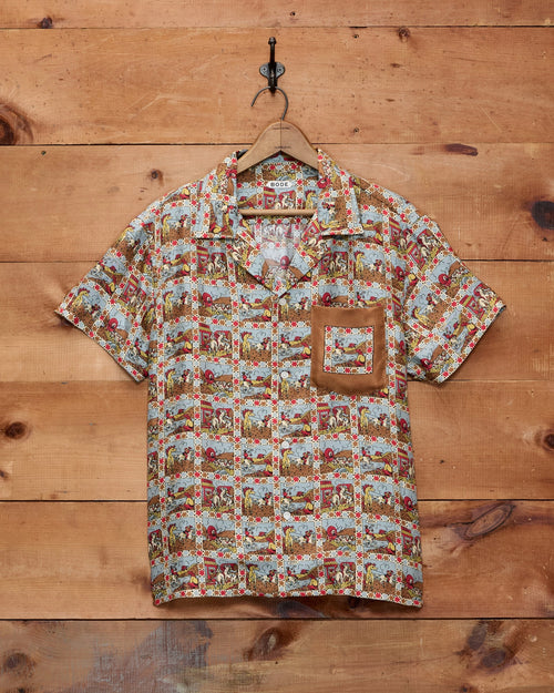 Bode Cowboy Comic Short Sleeve Shirt in multicolor silk with a repeating cowboy comic print and front patch pocket.