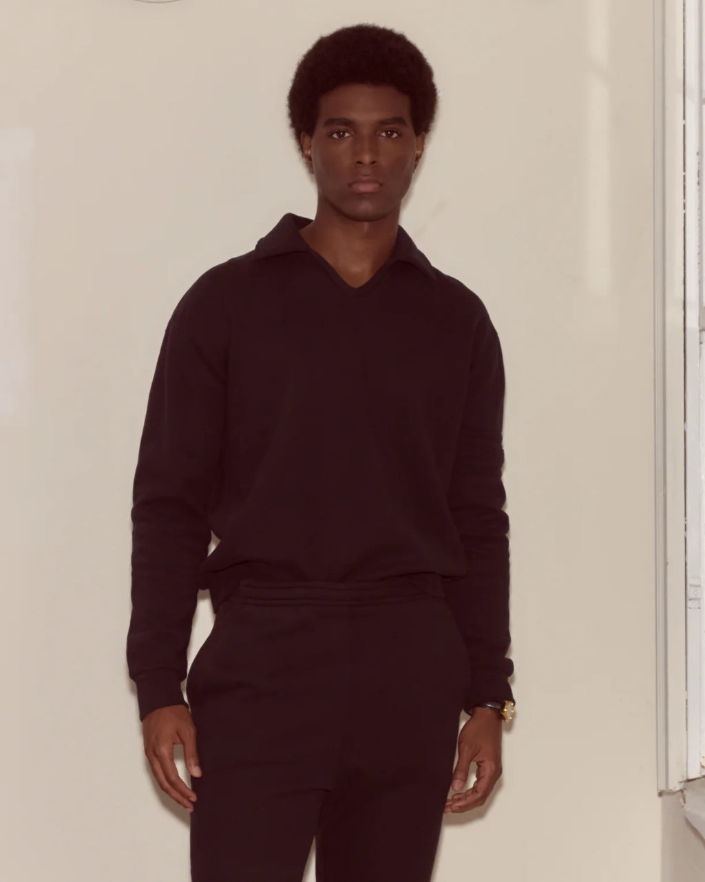 Person wearing a dark outfit against a plain background