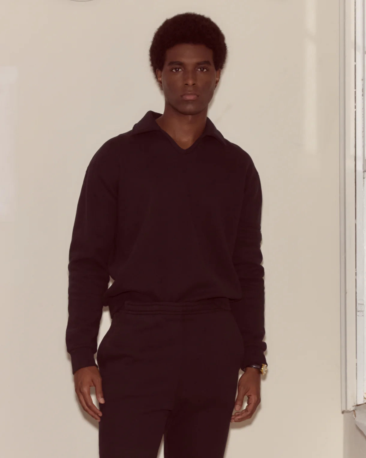Person wearing a dark outfit against a plain background