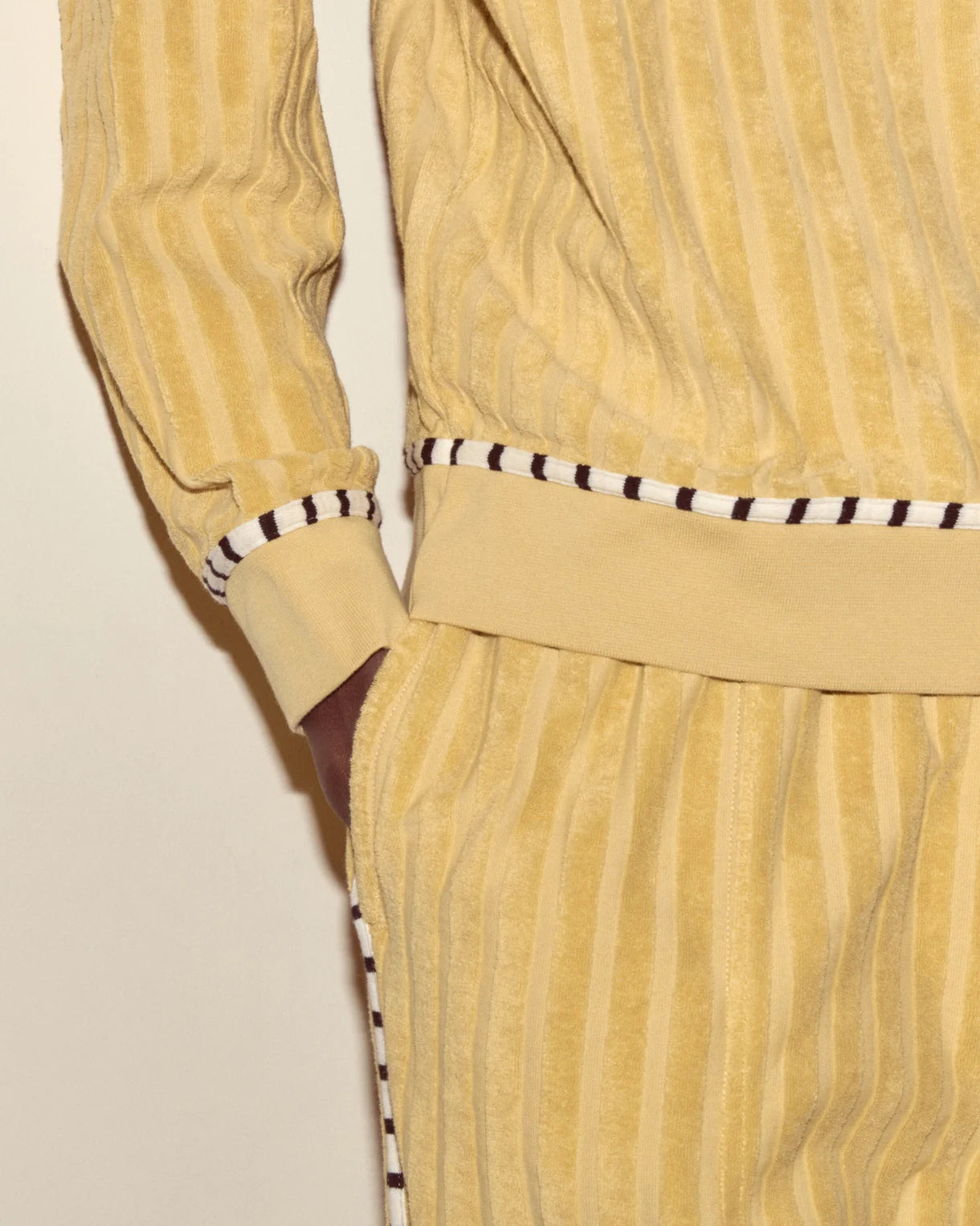 Yellow corduroy outfit with black and white striped details on a beige background