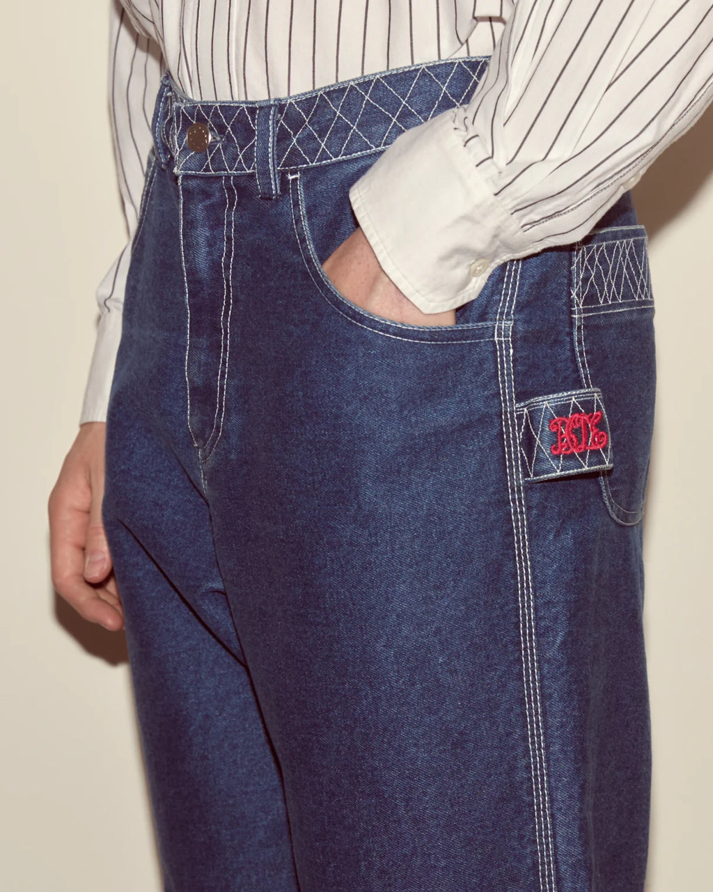 Blue apron with a brand logo worn by a person on a beige background