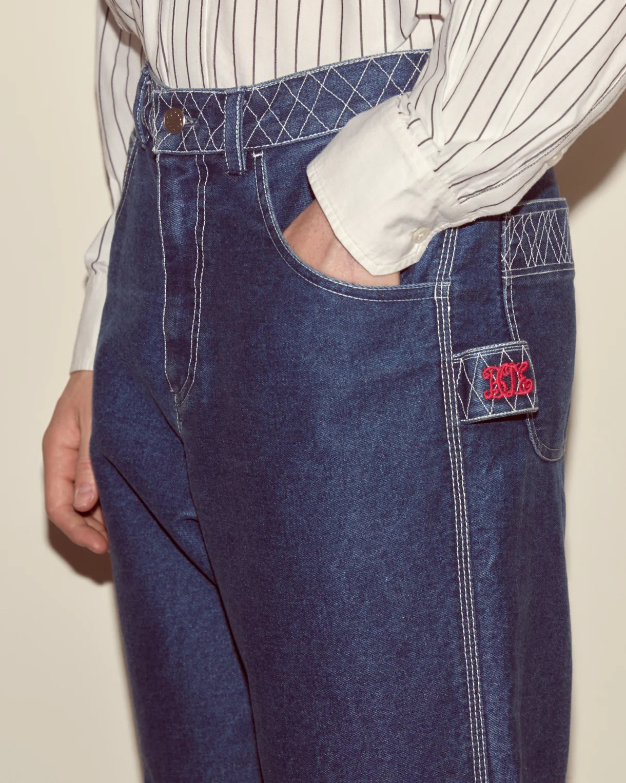 Blue apron with a brand logo worn by a person on a beige background