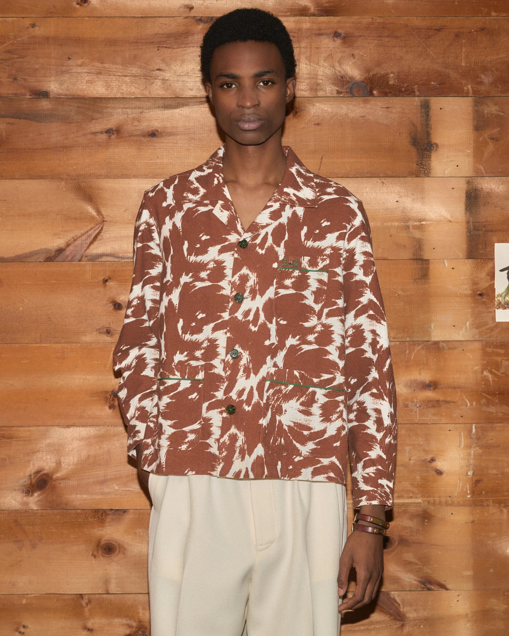 Model wearing Bode Flannel Cow Print Long Sleeve Shirt in brown and white cotton flannel with a boxy fit and three patch pockets.
