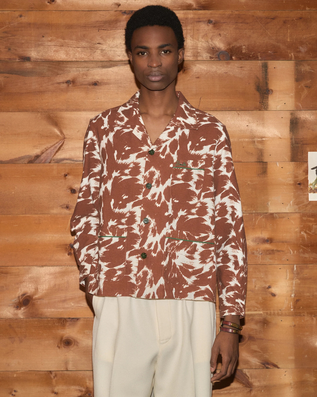 Model wearing Bode Flannel Cow Print Long Sleeve Shirt in brown and white cotton flannel with a boxy fit and three patch pockets.