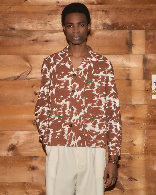 Model wearing Bode Flannel Cow Print Long Sleeve Shirt in brown and white cotton flannel with a boxy fit and three patch pockets.