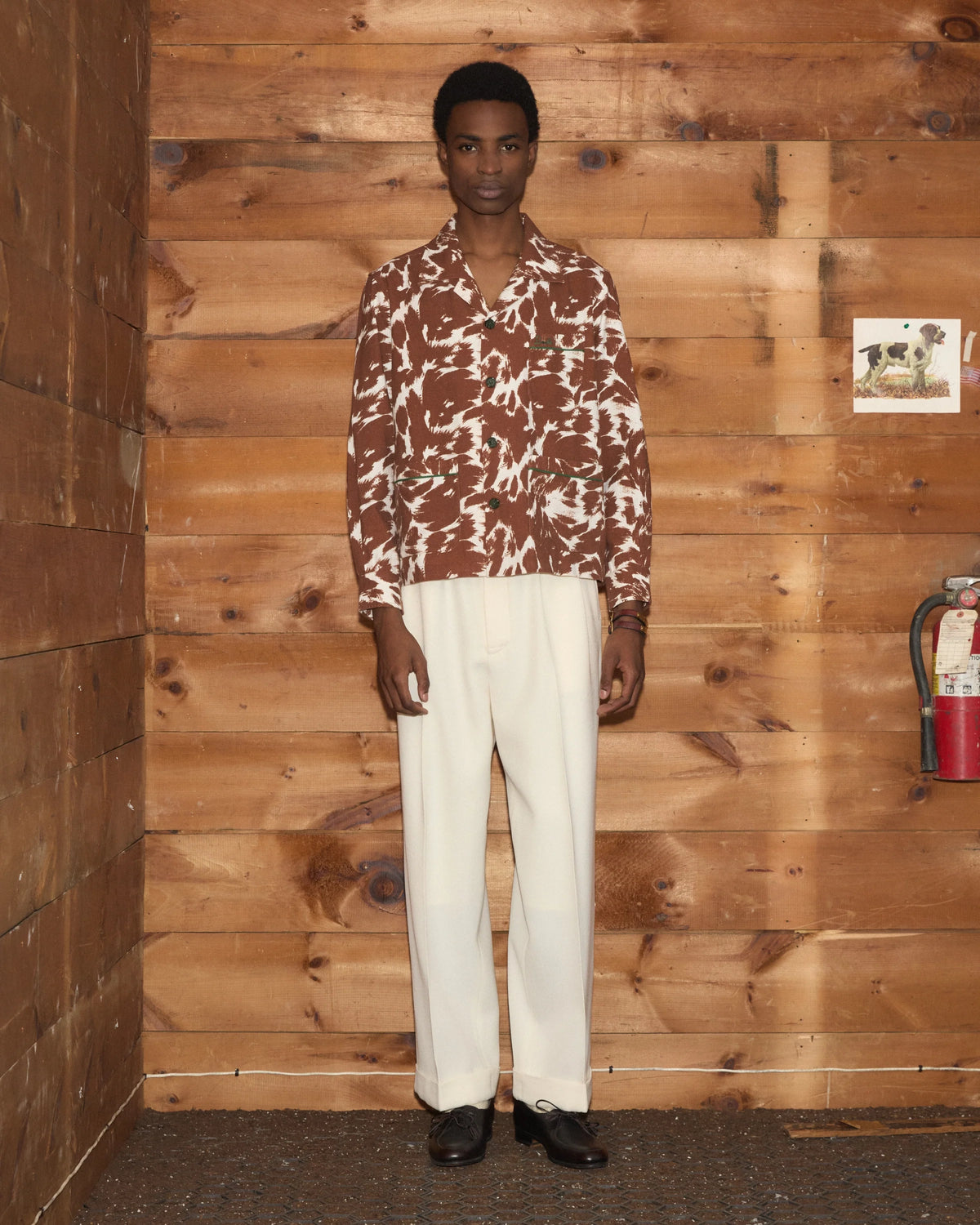 Model wearing Bode Flannel Cow Print Long Sleeve Shirt in brown and white cotton flannel with a boxy fit and three patch pockets.