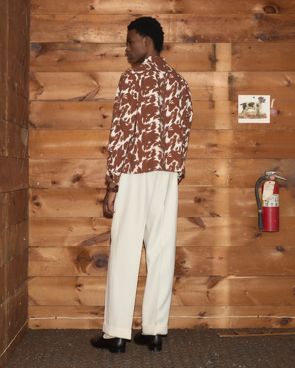Model wearing Bode Flannel Cow Print Long Sleeve Shirt in brown and white cotton flannel with a boxy fit and three patch pockets.