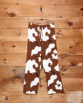 Bode Flannel Cow Print Pajama Pants in brown and white with green piping and cattle brand logo.