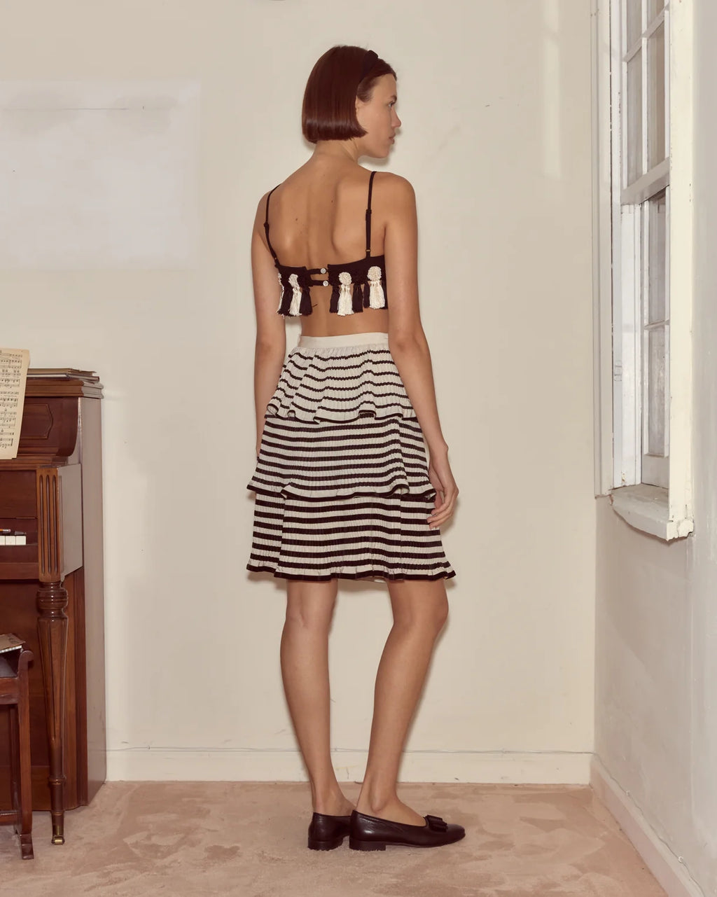 Woman wearing a black and white striped dress in a room with a piano.