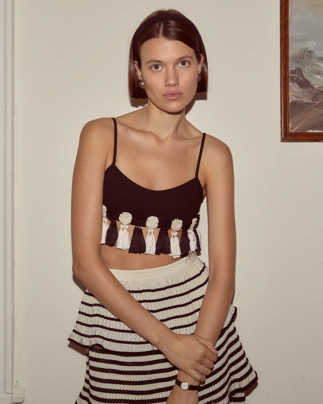 Woman wearing a black and white striped top and skirt against a plain wall.