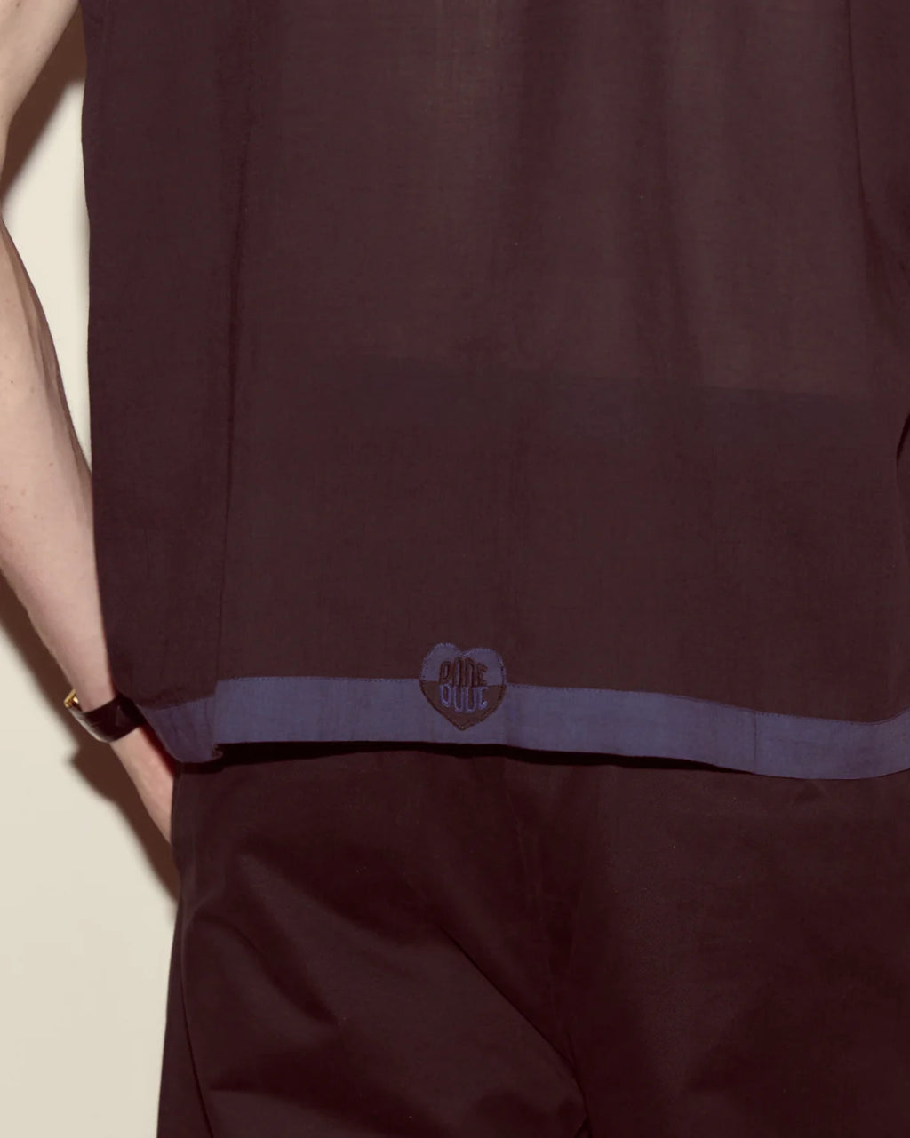 Dark brown garment with a brand logo on a light background