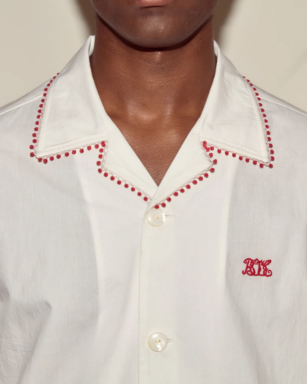 White shirt with red trim and a small logo on a plain background