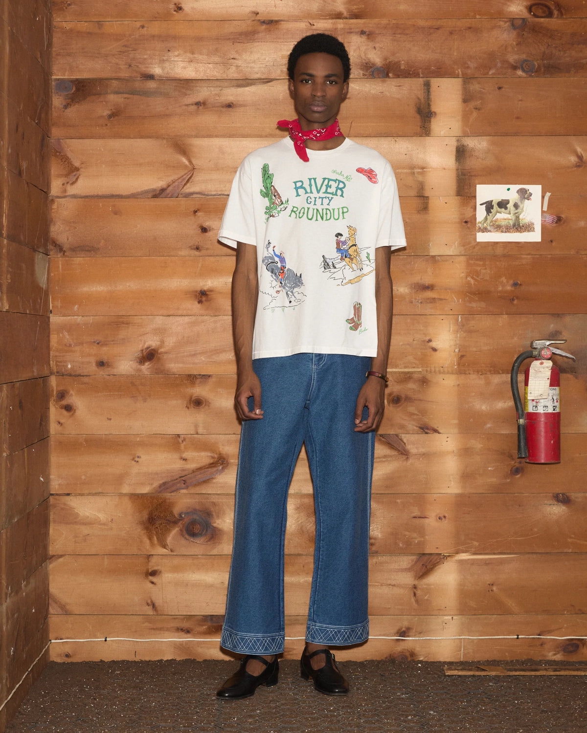Model wearing Bode River City Tee in white with a colorful River City Roundup graphic and Western-inspired illustrations.