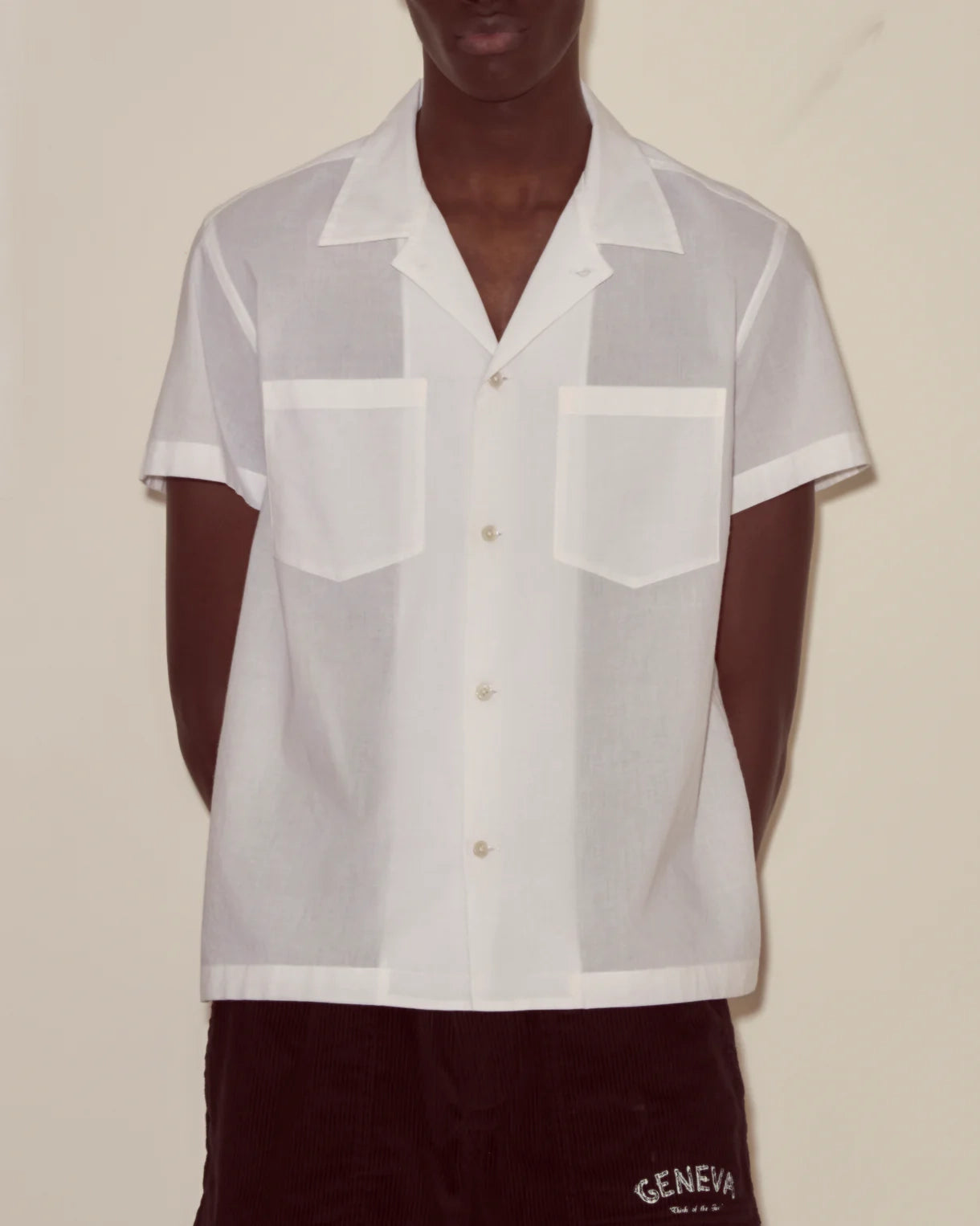 Person wearing a sheer white shirt over a dark garment with 'Geneva' branding.