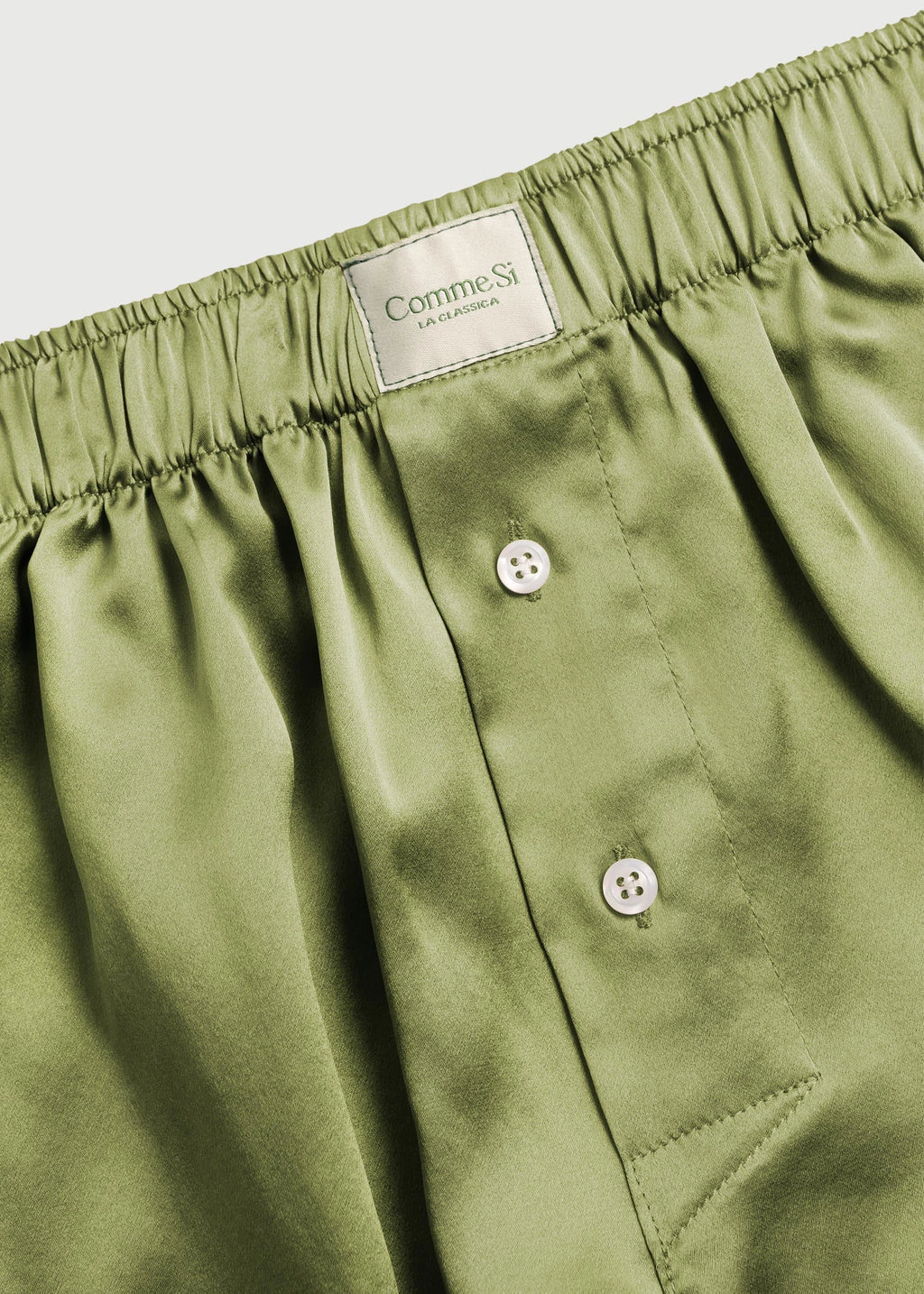 Green boxer shorts with a brand label on a light gray background
