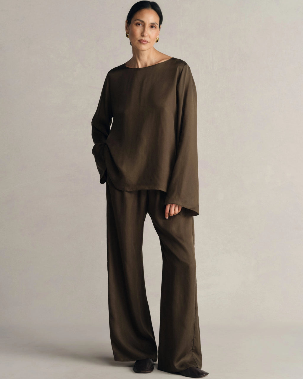 Model wearing Comme Si Everyday Pant in umber cupro twill with a wide-leg silhouette, fluid drape, and covered elastic waistband.