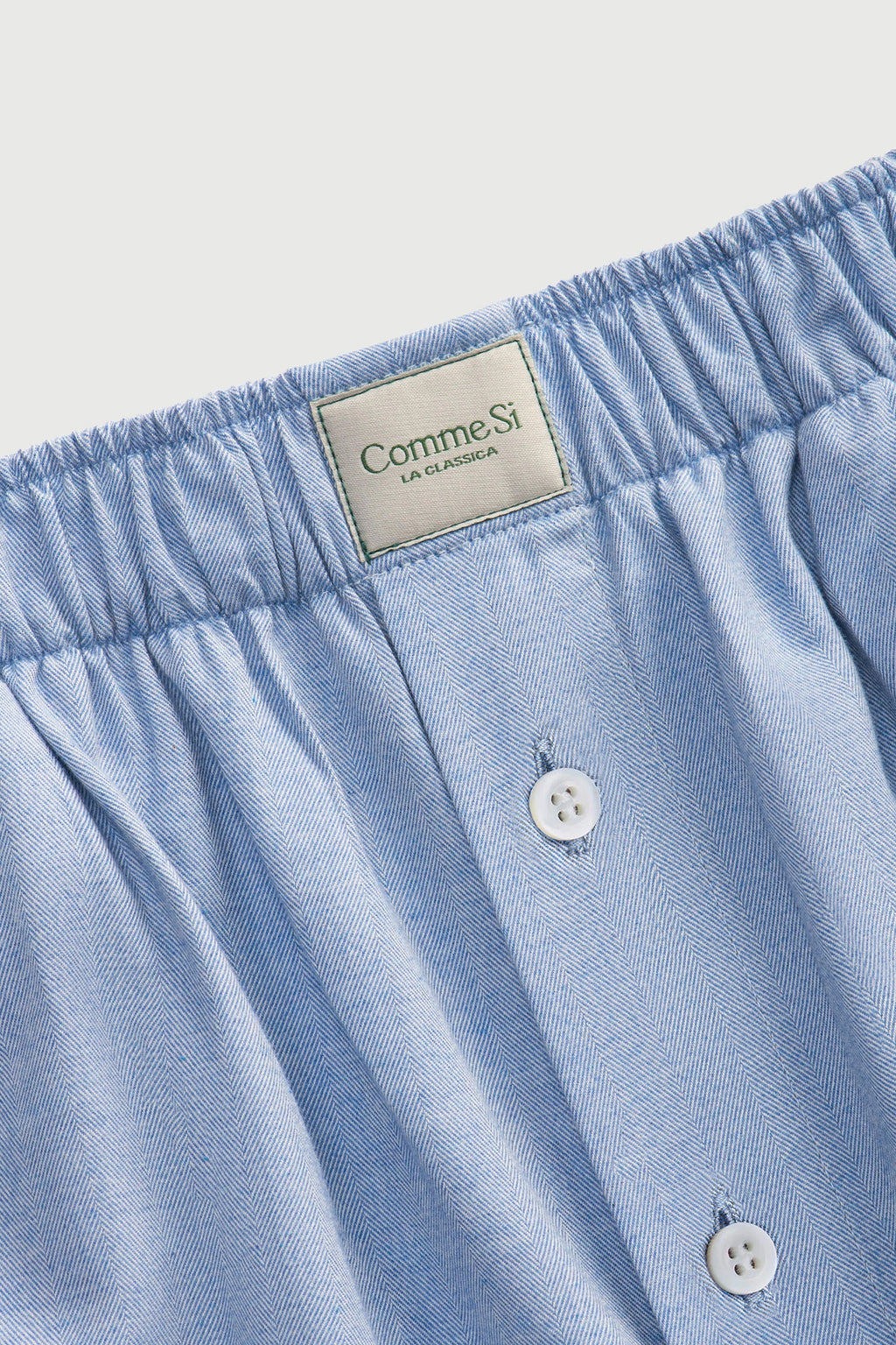 Light blue boxer shorts with a visible brand label on a light gray background