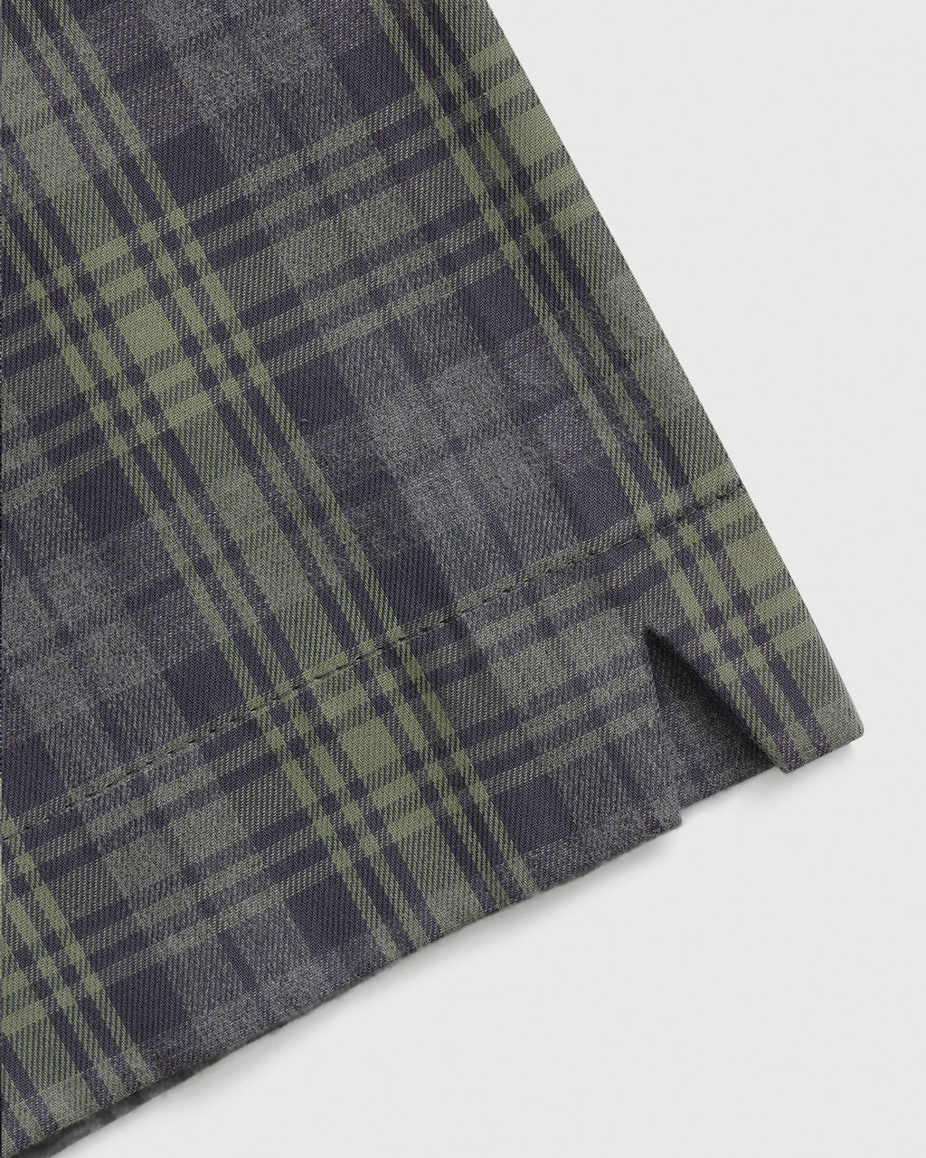 Detail view of ￼Comme Si La Boxer Alta in grey sage plaid cotton flannel with a wide-leg silhouette, covered elastic waistband, and side slits at the hem.