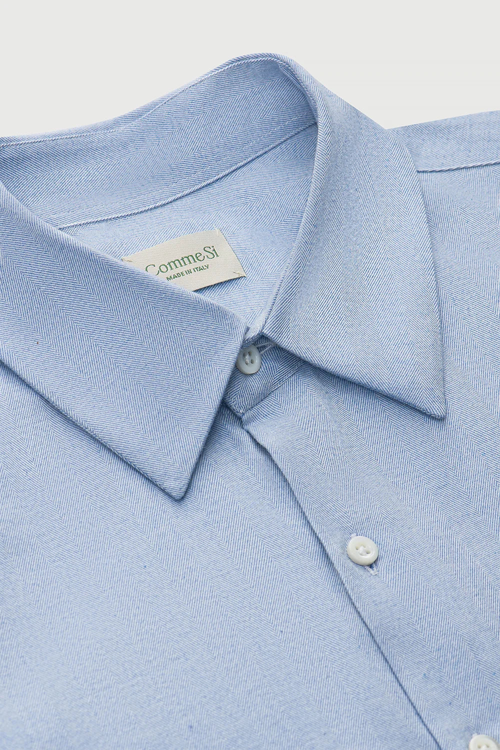 Light blue dress shirt with collar and buttons on a light gray background