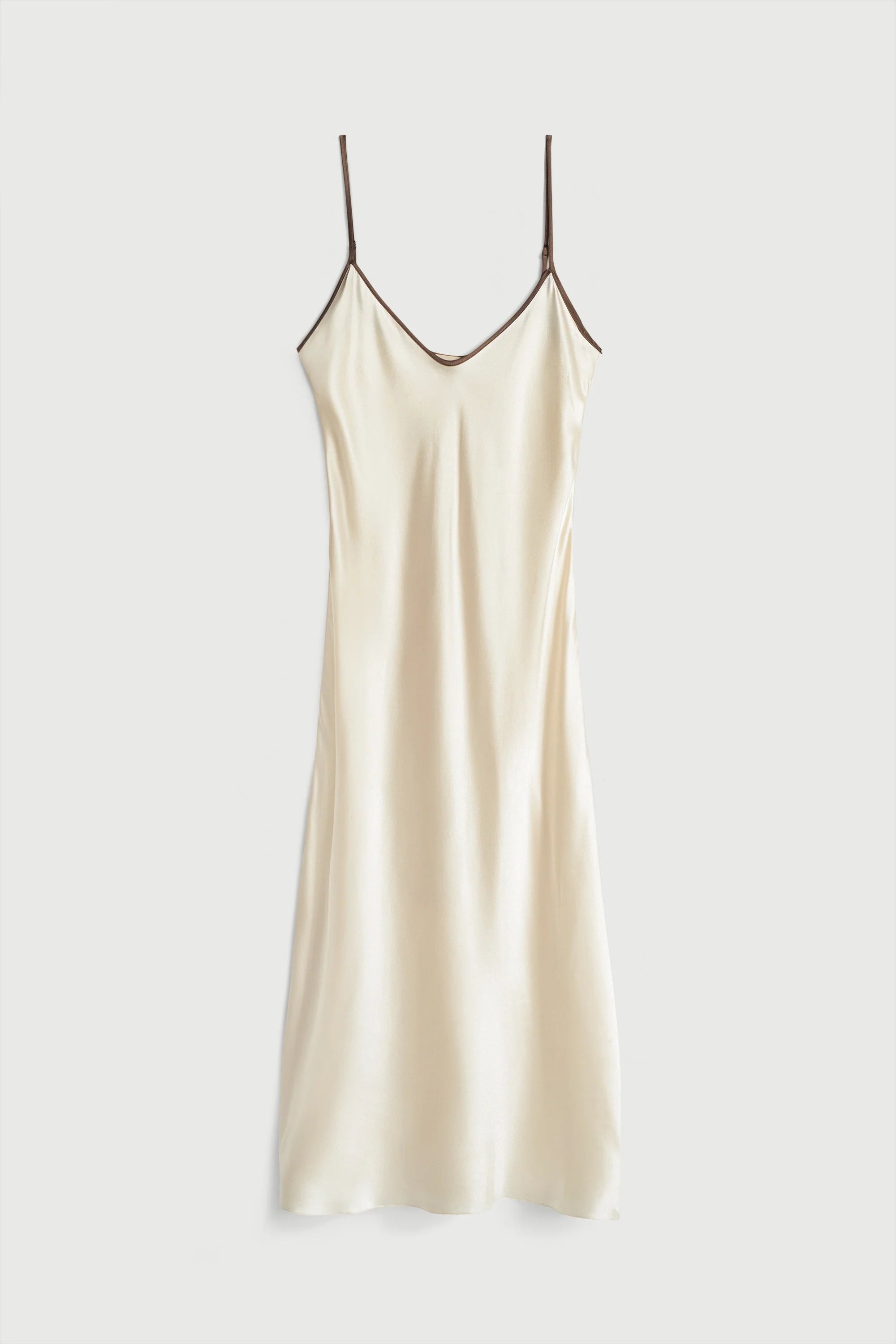 Beige slip dress with thin straps on a white background