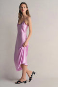 Woman wearing a pink slip dress against a plain background