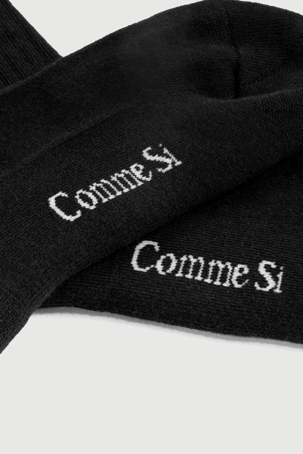 Black socks with 'Comme Si' branding on a white background