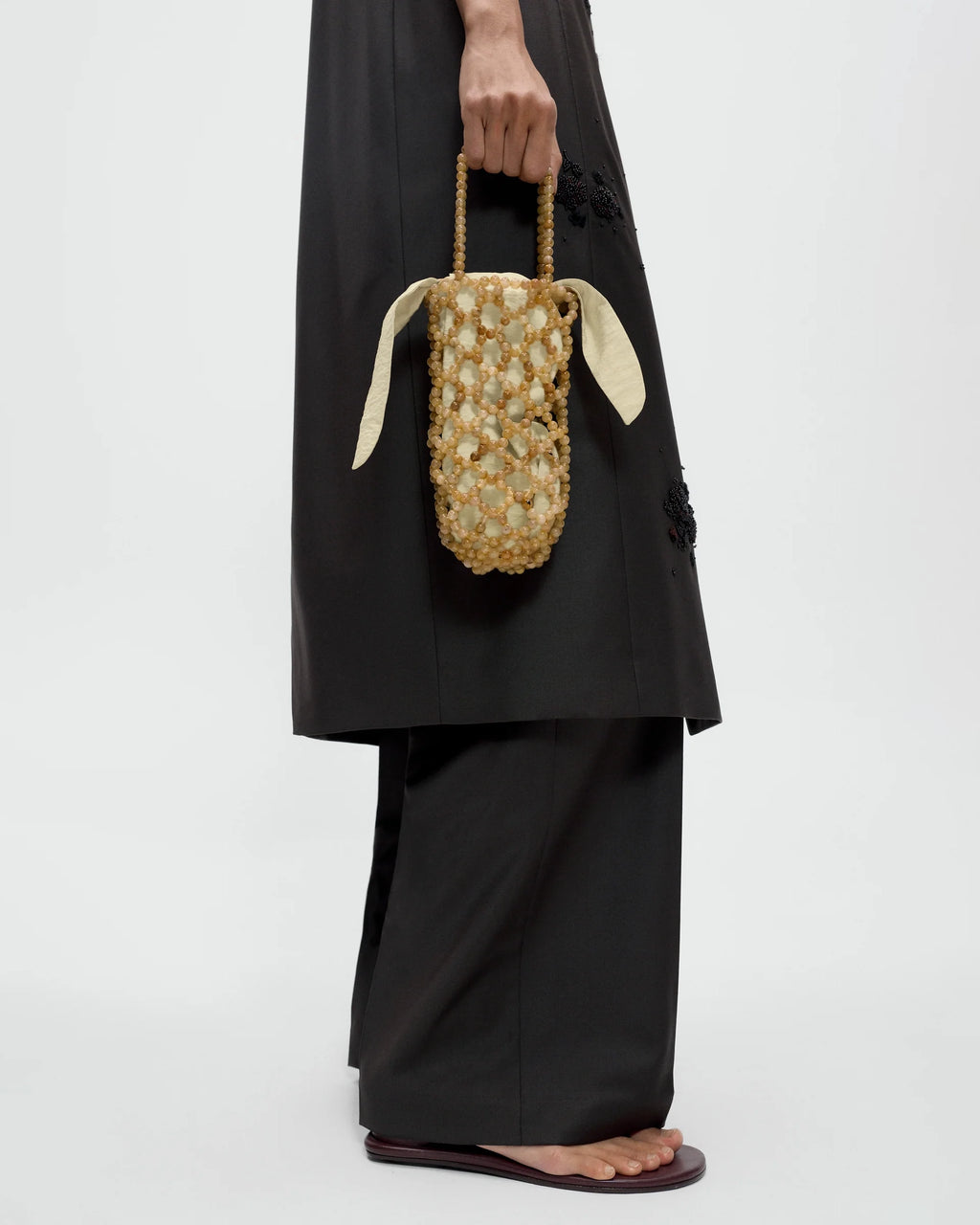 Model holding CORDERA Handmade Beaded Bag Jaspe Miel with a bottle-shaped silhouette and brown Ojo de Tigre beading.